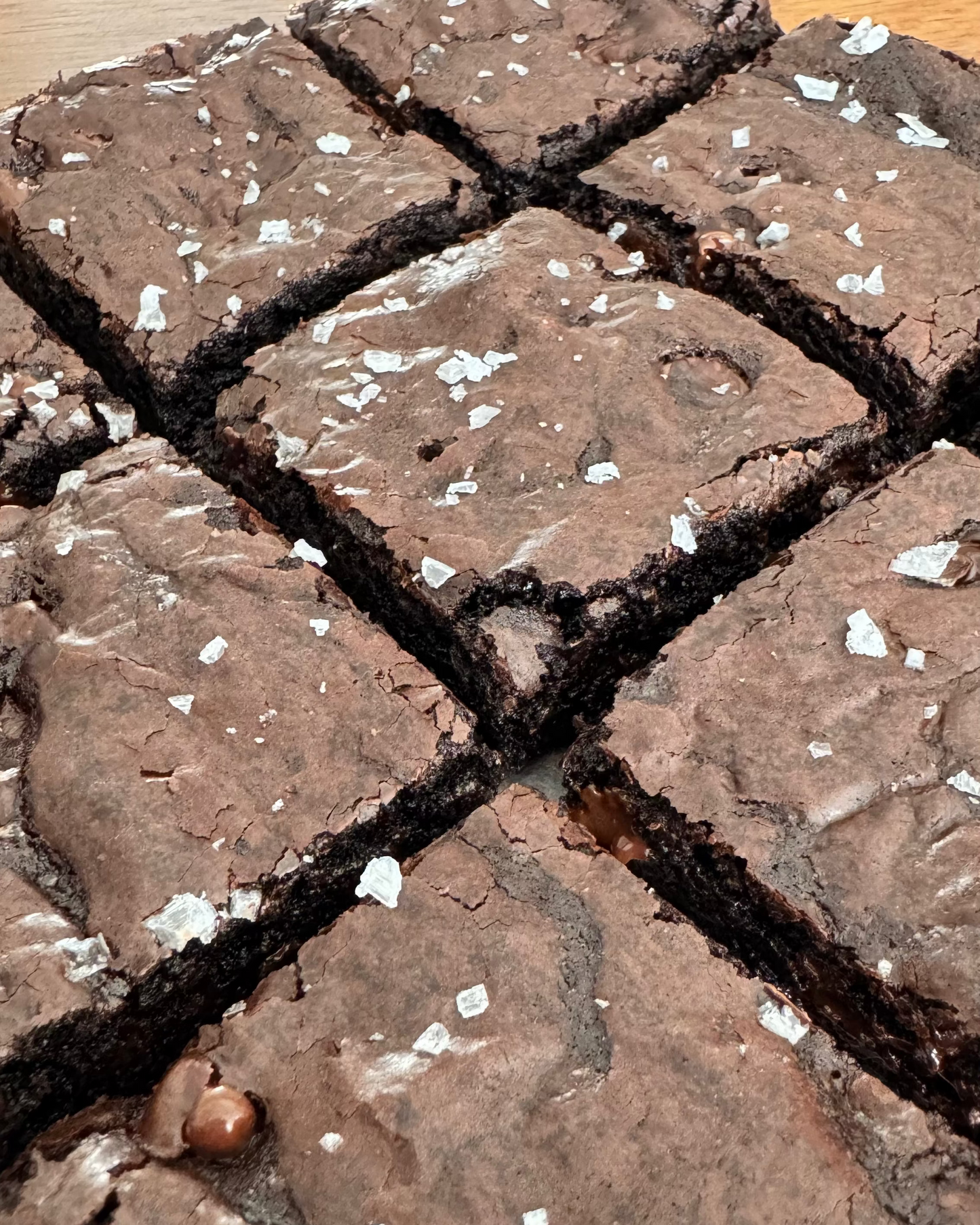 Close-up of freshly baked chocolate brownies cut into square sections, topped with coarse white sea salt flakes.