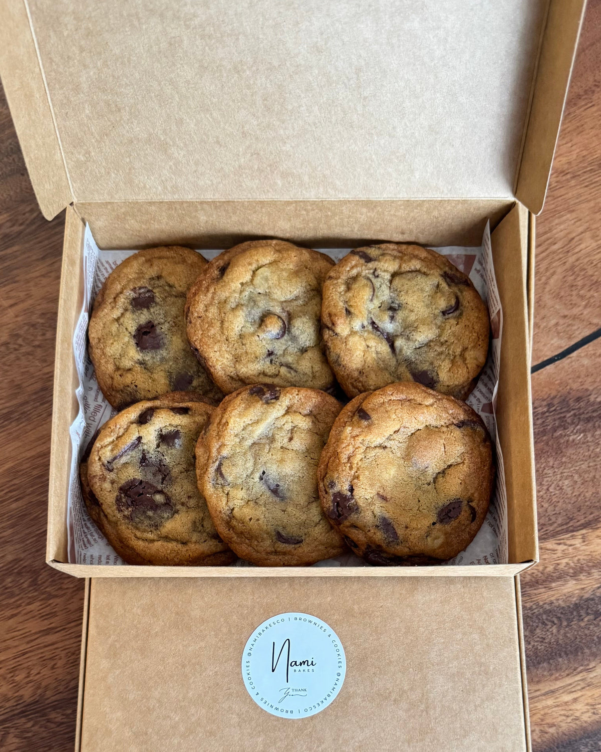 Open Nami Bakes box containing six dark chocolate chip cookies